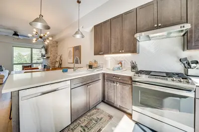 a kitchen with stainless steel appliances and wooden cabinets at Rooftop Mtn View and Hot Tub Silverthorne Home! in Silverthorne