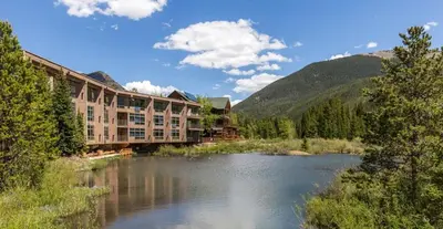 a hotel next to a river with mountains at Keystone W Magical View Walk to Ski Lift in Keystone