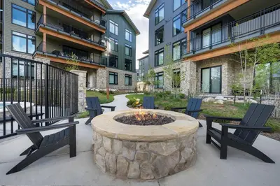 a patio with two chairs and a fire pit in front of some buildings at Ski Idlewild condo in Winter Park