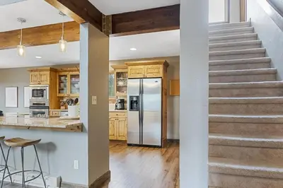 a kitchen with a staircase and a stainless steel refrigerator at Peaceful 5BR Retreat with Hot Tub in Breckenridge