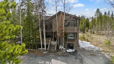 a house in the woods with a porch and stairs at Peaceful 5BR Retreat with Hot Tub in Breckenridge