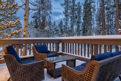 a deck with chairs and a table and snow covered trees at Peaceful 5BR Retreat with Hot Tub in Breckenridge