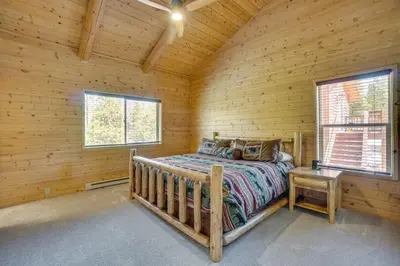a bedroom in a log cabin with a bed and two windows at Mountain-View Front Range Colorado Vacation Rental in Red Feather Lakes
