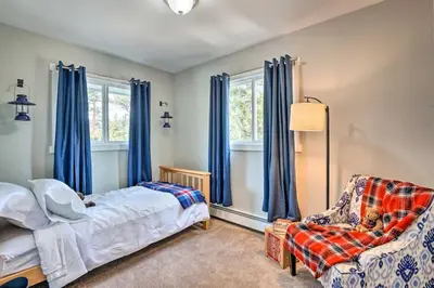 a bedroom with a bed and a chair and windows at 4 bed 2 bath home located near Rocky Mountain National Park in Estes Park
