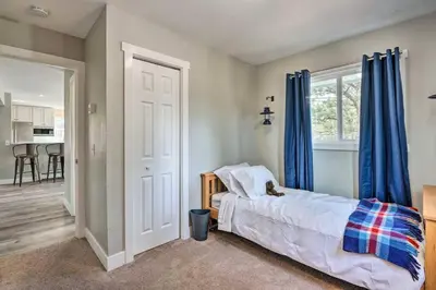 a bedroom with a bed with blue curtains and a kitchen at 4 bed 2 bath home located near Rocky Mountain National Park in Estes Park