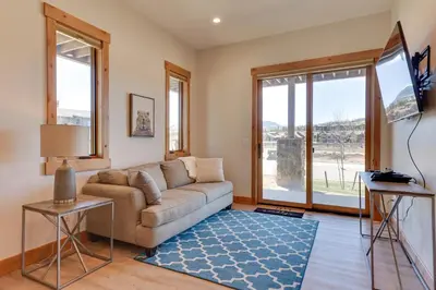 a living room with a couch and a tv at Fraser Getaway with Deck Near Winter Park Resort! in Fraser