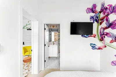 a room with a tv and purple flowers on the wall at The Acoma House in Denver