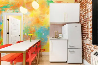a kitchen with white appliances and a table with red chairs at The Acoma House in Denver