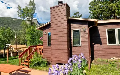 a tiny house with a bench and purple flowers at McGregor Mountain Lodge in Estes Park