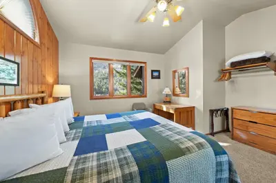 a bedroom with a bed and a dresser and windows at McGregor Mountain Lodge in Estes Park
