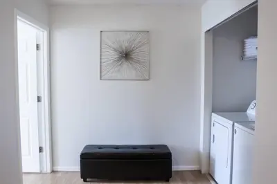 a white room with a black ottoman in front of a wall at Change Your Altitude in Denver 3BR near Denver Airport w/GameRoom in Denver