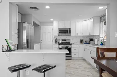 a kitchen with white cabinets and a counter with stools at Golfers Dream! Sweet NW location. in Arvada
