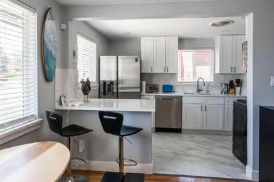 a kitchen with white cabinets and black chairs at Hidden Gem of Arvada! in Arvada