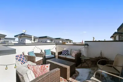 a patio with couches and chairs on a roof at 2 BDR Home Roof Deck plus Walk to Broncos and Sloans Lake in Denver