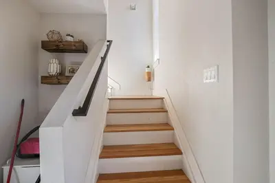 a staircase in a home with white walls and wooden floors at 2 BDR Home Roof Deck plus Walk to Broncos and Sloans Lake in Denver