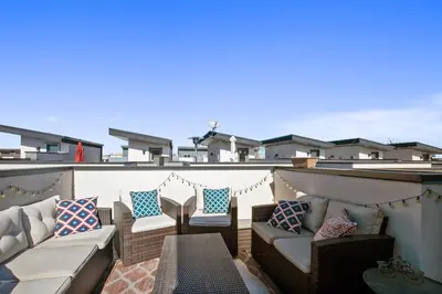 a patio with chairs and couches on a roof at 2 BDR Home Roof Deck plus Walk to Broncos and Sloans Lake in Denver