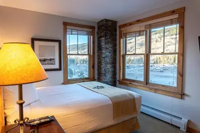 a bedroom with a bed with a lamp and windows at 2BR Ski In Ski Out Keystone Condo Walk to Slopes in Dillon