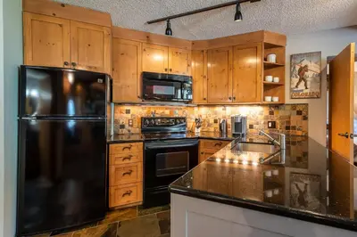 a kitchen with wooden cabinets and a black refrigerator at Iron Horse C5013 condo in Winter Park