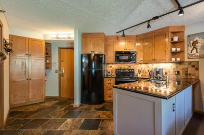 a kitchen with wooden cabinets and a black refrigerator at Iron Horse C5013 condo in Winter Park