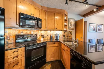 a kitchen with wooden cabinets and a black stove top oven at Iron Horse C5013 condo in Winter Park