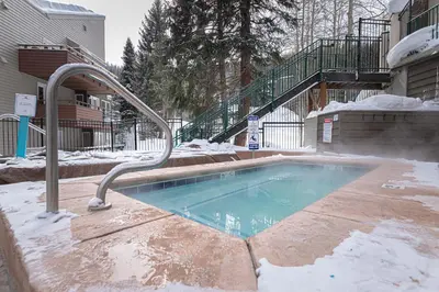 a swimming pool covered in snow with a metal hand rail at Iron Horse C3013 condo in Winter Park