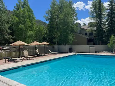 a swimming pool with chairs and umbrellas in a yard at 2BR Keystone Condo Near Slopes in Keystone