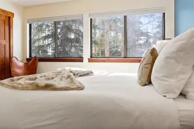 a white bed with a blanket on it with windows at 2BR Keystone Condo Near Slopes in Keystone