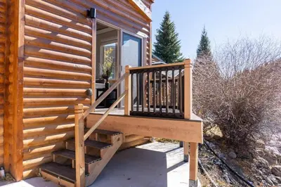 a wooden cabin with a staircase leading to a porch at 2BR Riverside Cabin Near Trails with Hot Tub Access in Breckenridge