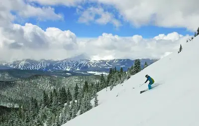 a man is skiing down a snow covered mountain at 2BR Riverside Cabin Near Trails with Hot Tub Access in Breckenridge