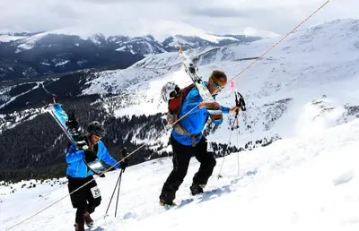 two people walking up a mountain with skis on their backs at 2BR Riverside Cabin Near Trails with Hot Tub Access in Breckenridge