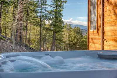 a hot tub with a view of the woods at BEST VIEWS! Luxury Mountain Home - Saltwater HotTub, Firepit, BBQ- Close to SKI, Red Rocks in Evergreen