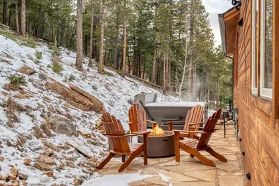 a patio with two chairs and a grill in the snow at BEST VIEWS! Luxury Mountain Home - Saltwater HotTub, Firepit, BBQ- Close to SKI, Red Rocks in Evergreen