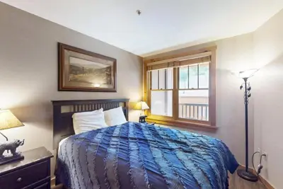 a bedroom with a bed with a blue blanket and a window at Buffalo Lodge 1 Bedroom In River Run in Keystone