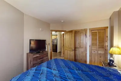 a bedroom with a blue bed and a flat screen tv at Buffalo Lodge 1 Bedroom In River Run in Keystone