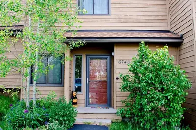 a house with a red door and some bushes at Cozy 2BR with Great Views Near Trails in Silverthorne