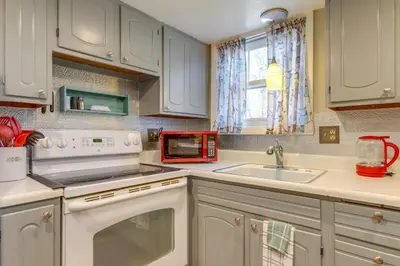 a kitchen with white cabinets and a sink and a window at 8 Mi to Dtwn Denver Wheat Ridge Gem with Patio in Wheat Ridge