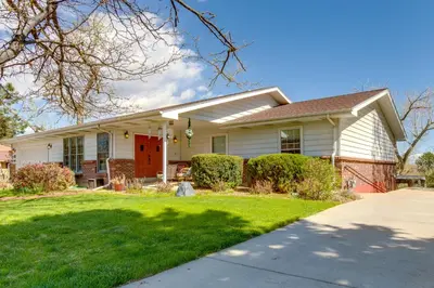 a white house with a red door and a yard at 8 Mi to Dtwn Denver Wheat Ridge Gem with Patio in Wheat Ridge