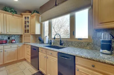 a kitchen with wooden cabinets and a sink and a window at 1 Mi to Cherry Creek State Park Home with Game Room in Centennial