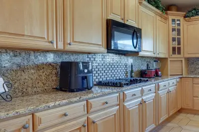a kitchen with wooden cabinets and a stove and microwave at 1 Mi to Cherry Creek State Park Home with Game Room in Centennial