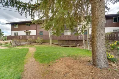 a house with a tree in the yard at Riverfront Condo Near Downtown Estes Park! in Estes Park
