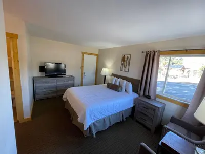 a bedroom with a bed and a tv and a window at Estes Mountain Inn in Estes Park