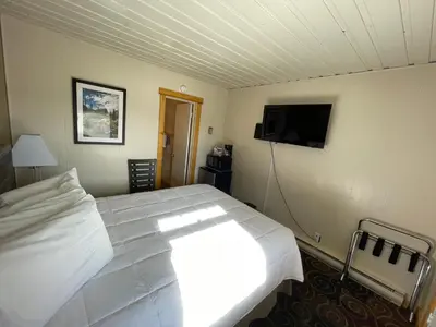 a bedroom with a white bed and a flat screen tv at Estes Mountain Inn in Estes Park