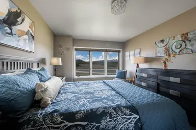 a bedroom with a blue bed and a window at Lake Dillon Retreat Townhome: Panoramic Lake, Mountain Views in Dillon
