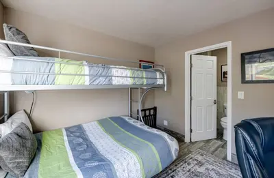 a bedroom with two bunk beds and a bathroom at Lake Dillon Retreat Townhome: Panoramic Lake, Mountain Views in Dillon