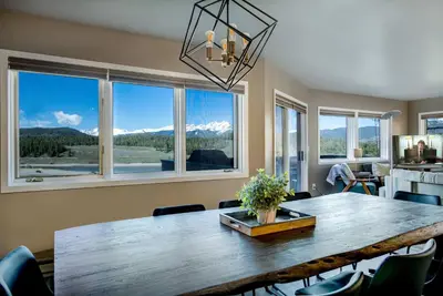 a dining room with a large wooden table and windows at Lake Dillon Retreat Townhome: Panoramic Lake, Mountain Views in Dillon