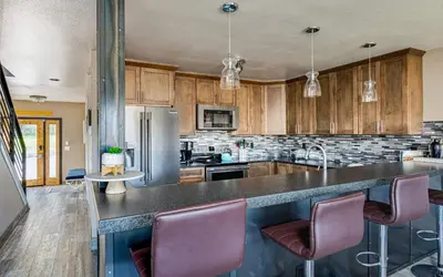 a kitchen with wooden cabinets and a counter with chairs at Lake Dillon Retreat Townhome: Panoramic Lake, Mountain Views in Dillon