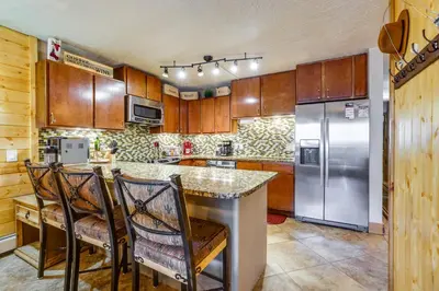 a kitchen with wooden cabinets and stainless steel appliances at 1 Mi to Marina Frisco Condo with Mtn-View Balcony! in Frisco
