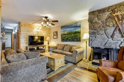 a living room with couches and a stone fireplace at 1 Mi to Marina Frisco Condo with Mtn-View Balcony! in Frisco