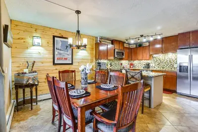 a kitchen with a wooden table and chairs and a refrigerator at 1 Mi to Marina Frisco Condo with Mtn-View Balcony! in Frisco