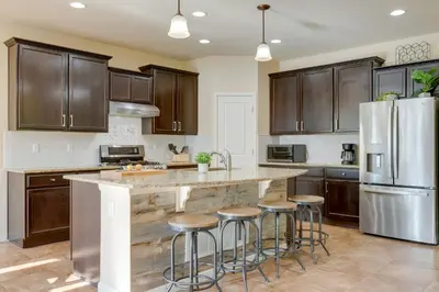 a kitchen with wooden cabinets and a large island with bar stools at Westminster Home with Patio and BBQ Near Dtwn Denver in Westminster
